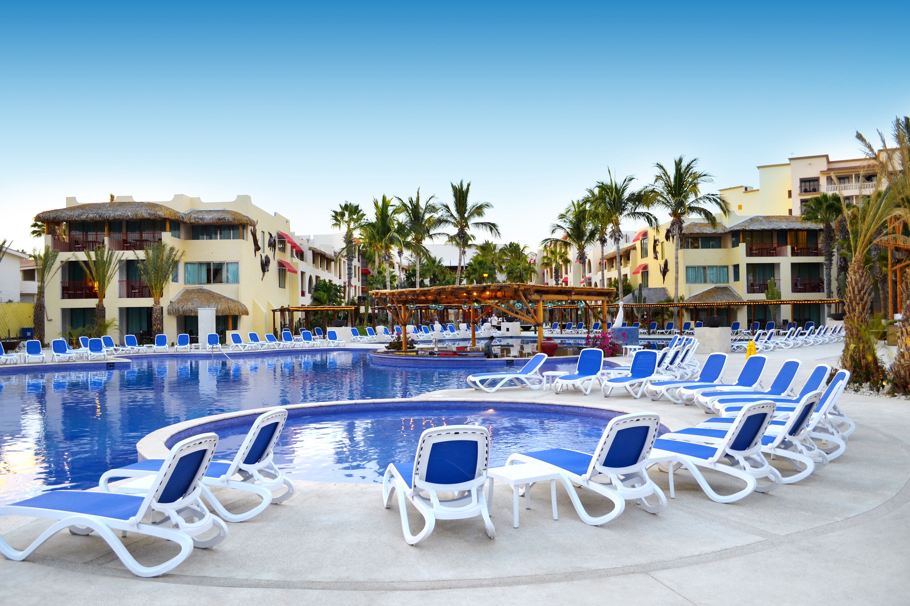 A pool area with lounge chairs and a thatched-roof structure.
