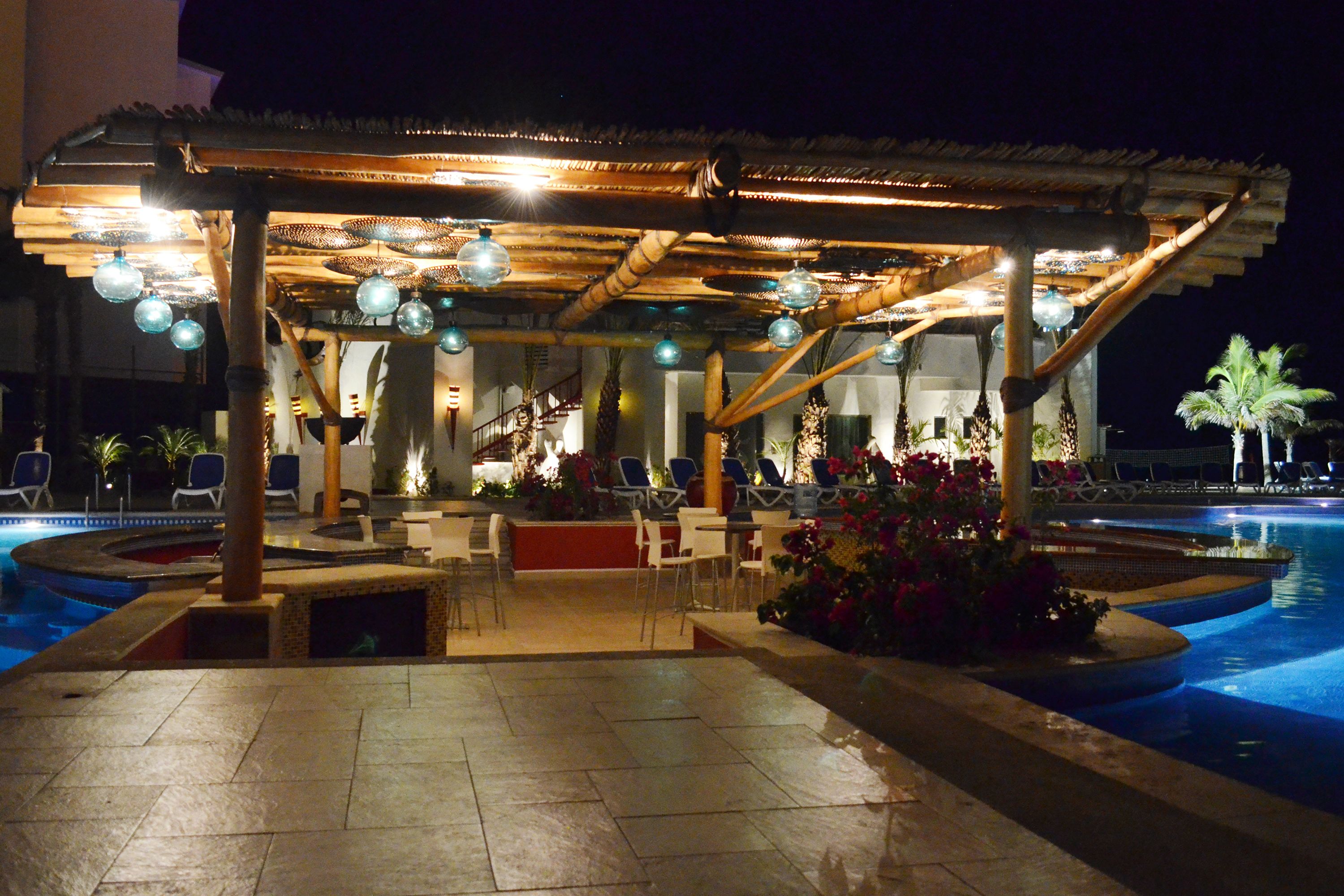 A poolside area with a covered seating area, lounge chairs, and a pool.