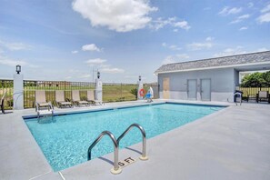 A swimming pool with a lifeguard stand, lounge chairs, and a covered area with doors.
