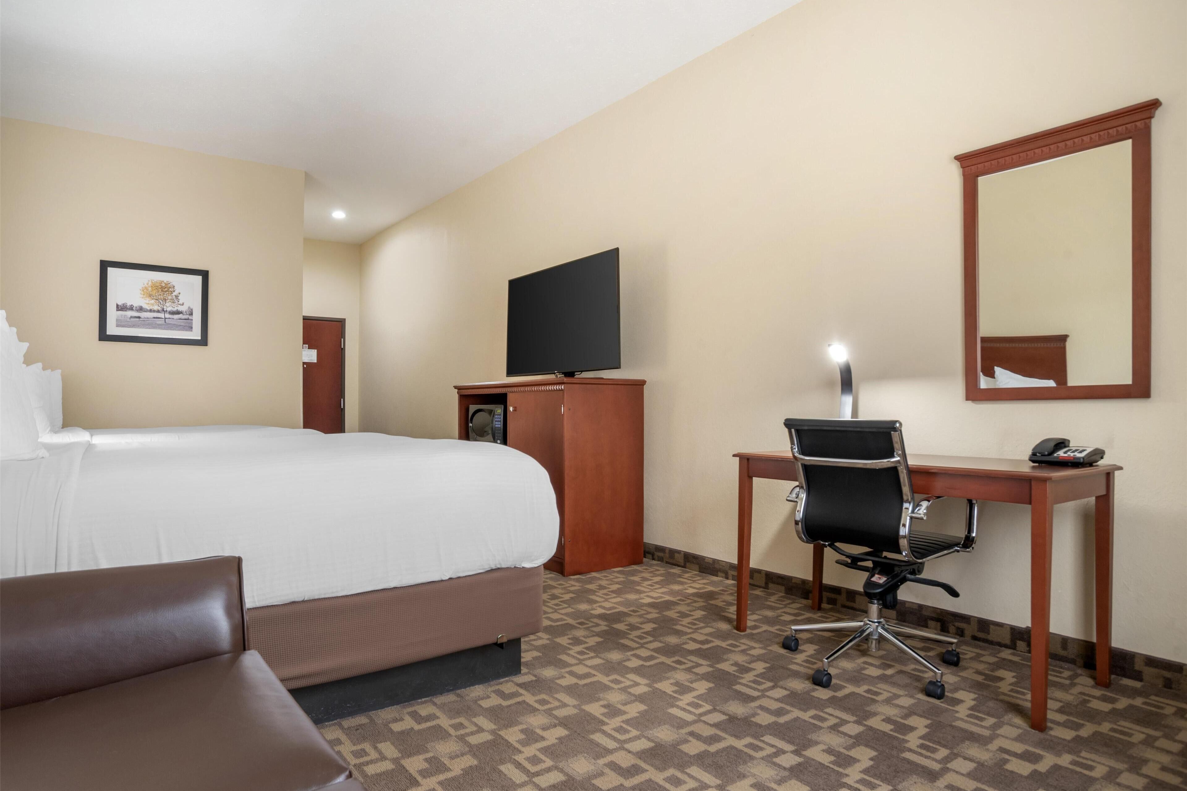 Une chambre d’hôtel équipée d’un lit, d’un bureau, d’une chaise, d’une télévision et d’un miroir.