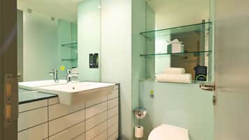 Een moderne badkamer met een grote spiegel, een wastafel, een toilet en een glazen plank met toiletartikelen.