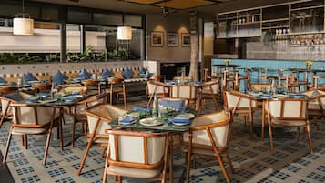 A restaurant with round tables, wicker chairs, and a tiled floor.