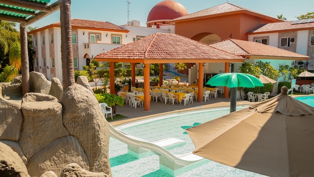 A pool area with a slide, outdoor seating, and a covered pavilion. - Hotel Maria Isabel (Colima)