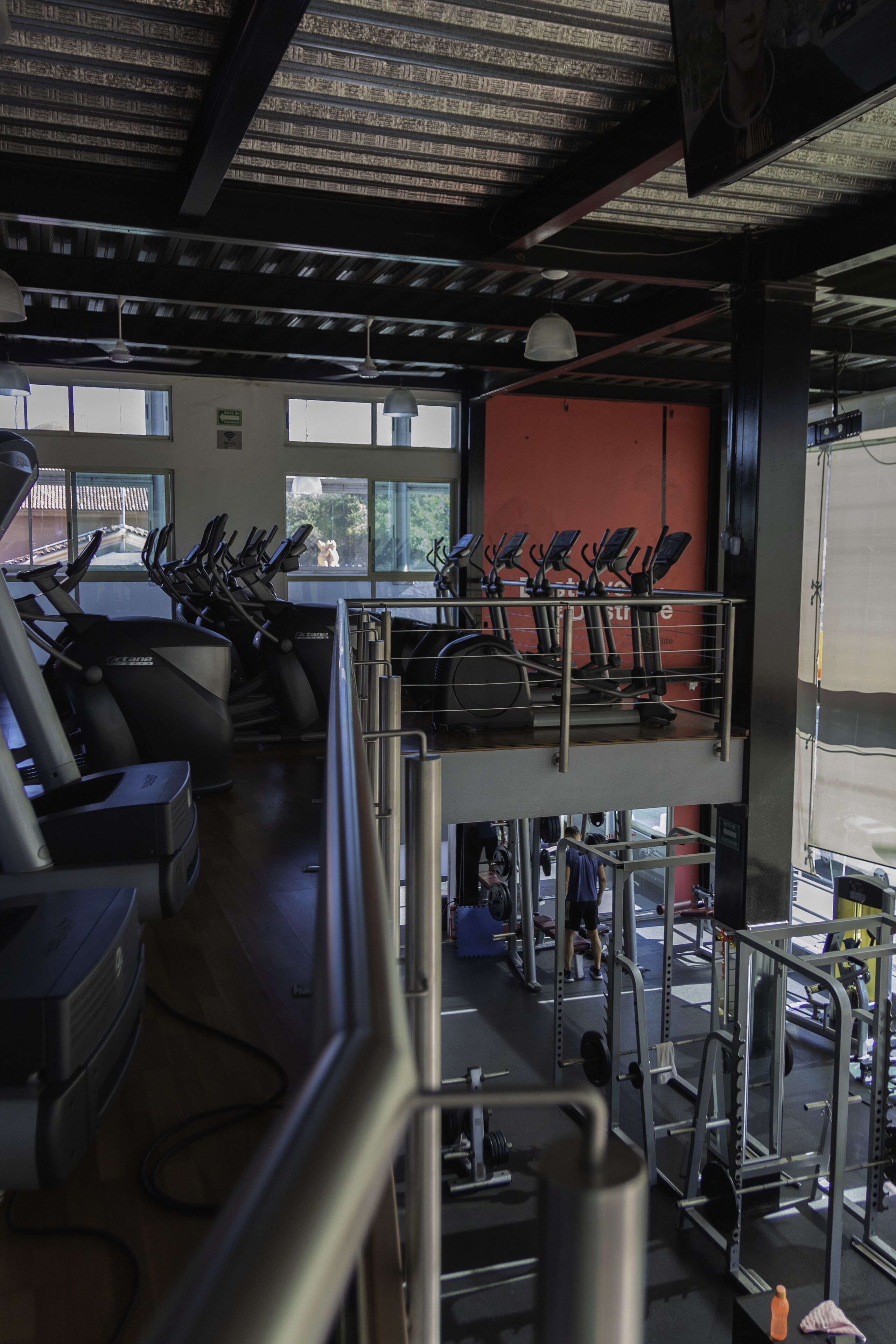 A gym with treadmills, weight machines, and a mezzanine level.
