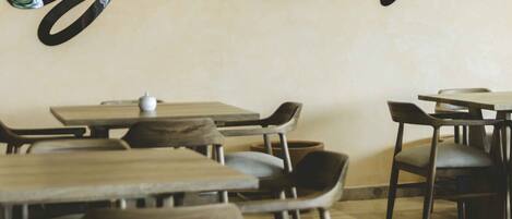 A restaurant interior with tables and chairs, a wall with the name 'Guacamex' in a stylized font, and a small white object on one table.