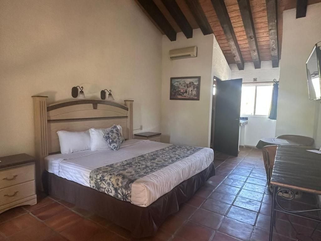A bedroom with a bed, bedside tables, a desk, and a chair.