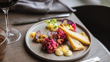 Ein Teller Essen mit Brot, Gemüse und einem Glas Wein auf einem Tisch.