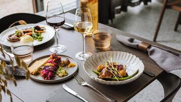 Una mesa de comedor con platos de comida, copas de vino y cubiertos.