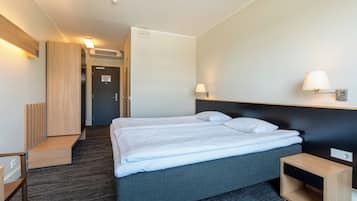 Una habitación de hotel con cama, mesitas de noche, armario y lámpara.