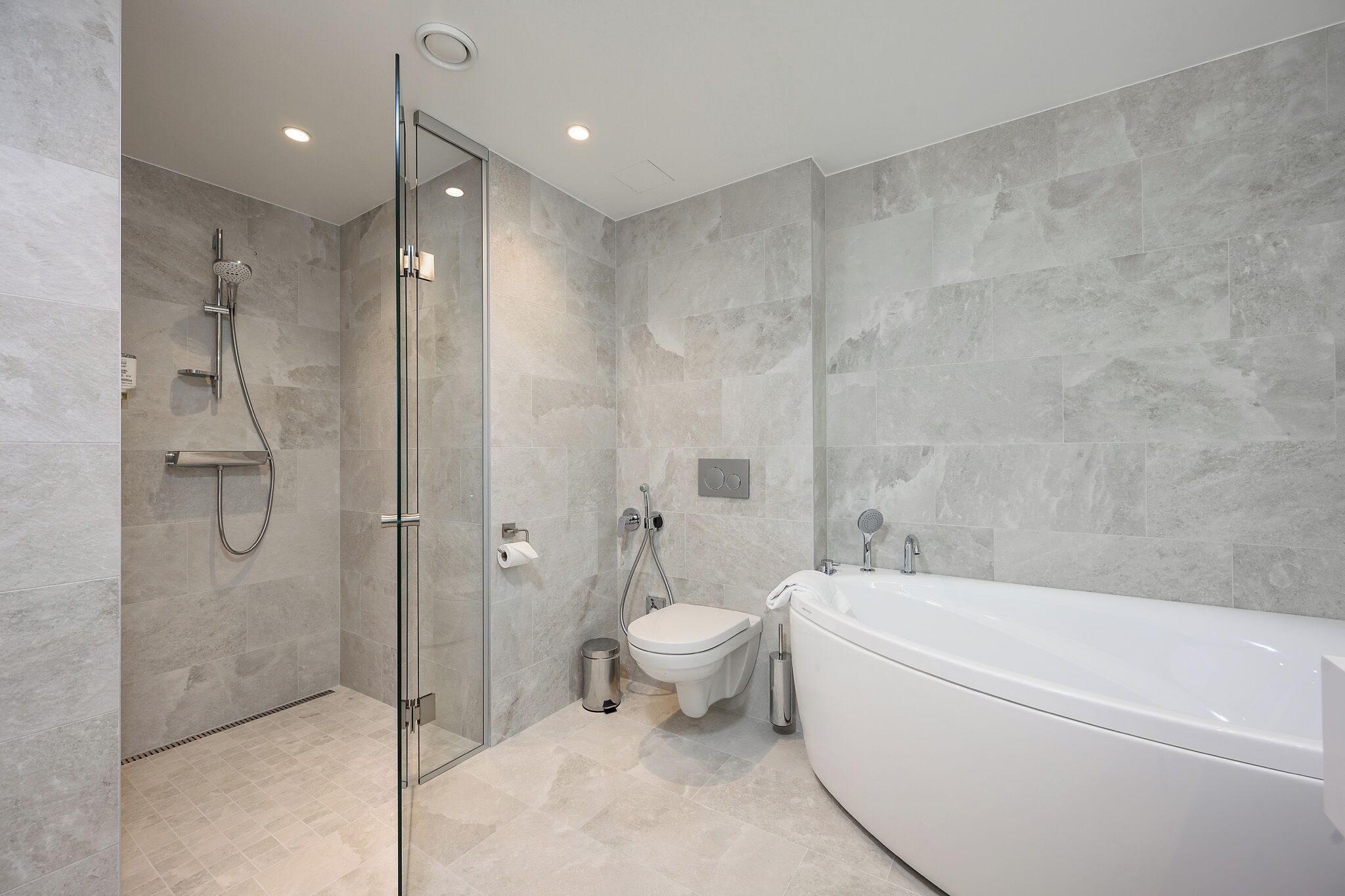 A modern bathroom with a glass-enclosed shower, a toilet, and a freestanding bathtub.