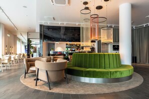 A modern lounge area with a green sofa, beige armchairs, and a circular rug. - Dorpat Hotel (Tartu)