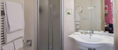 A modern bathroom with a glass-enclosed shower, a white sink with a mirror, and a towel rack.