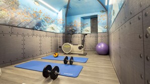 Een sportschool met blauwe matten, gewichthefapparatuur en een grote fitnessbal.