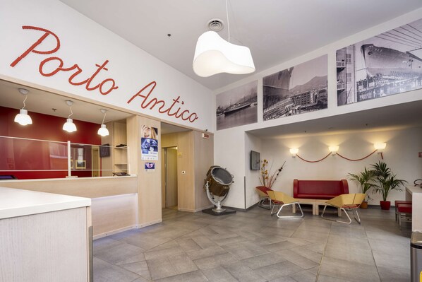 A lobby with a reception desk, a red sofa, and a mirror. - Best Western Hotel Porto Antico (Genoa)