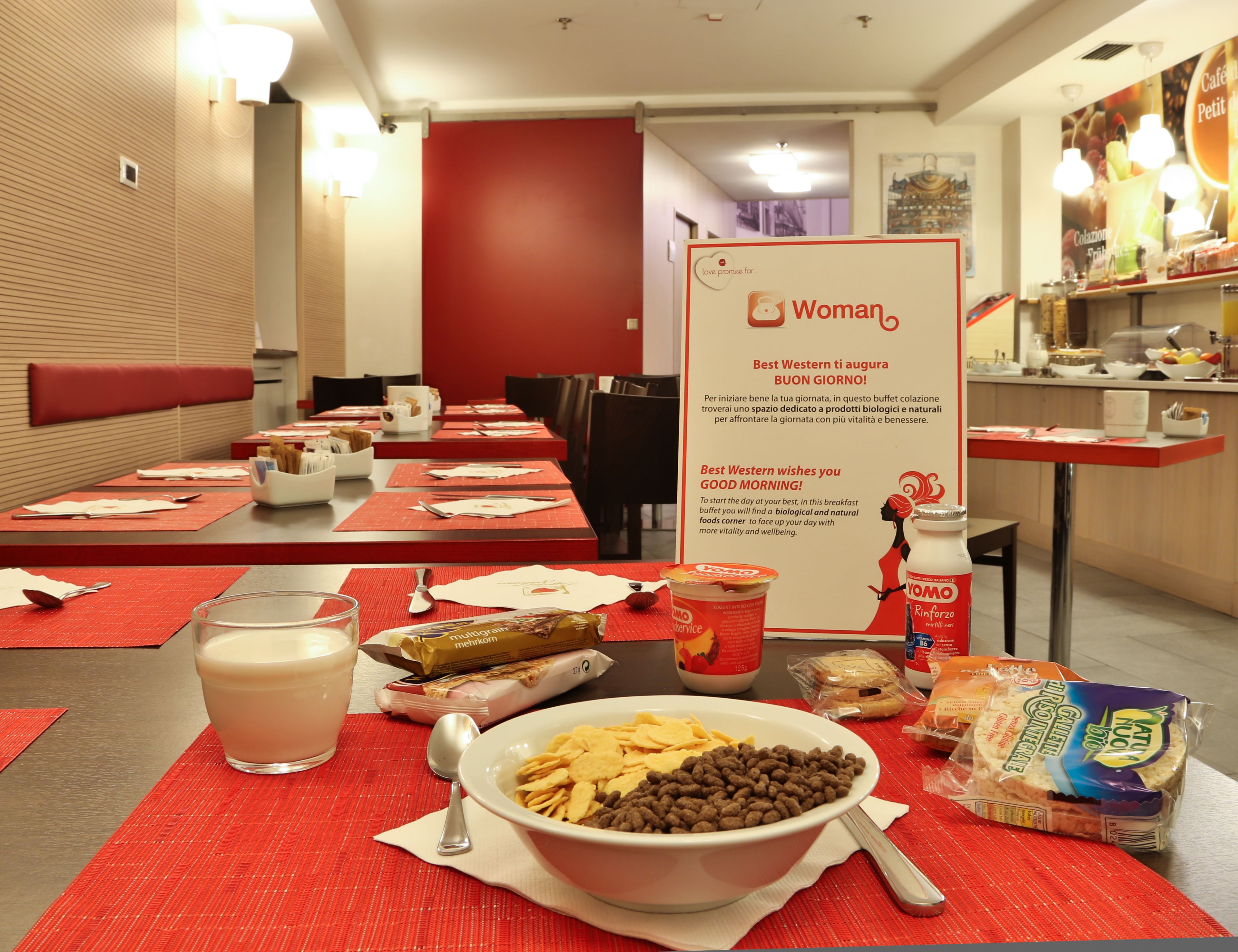 A breakfast buffet setup with various food items and a sign promoting a woman-focused message.