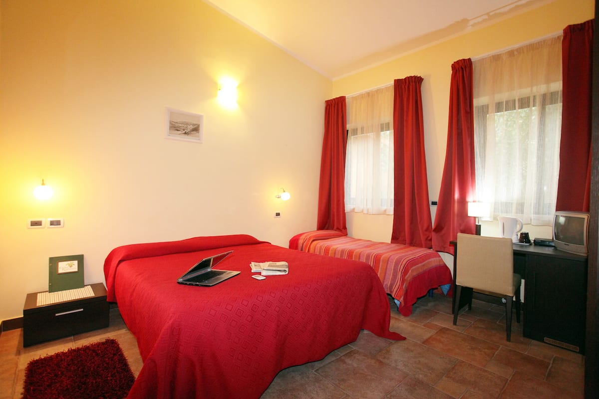 A hotel room with two beds, a desk with a computer, and a television.