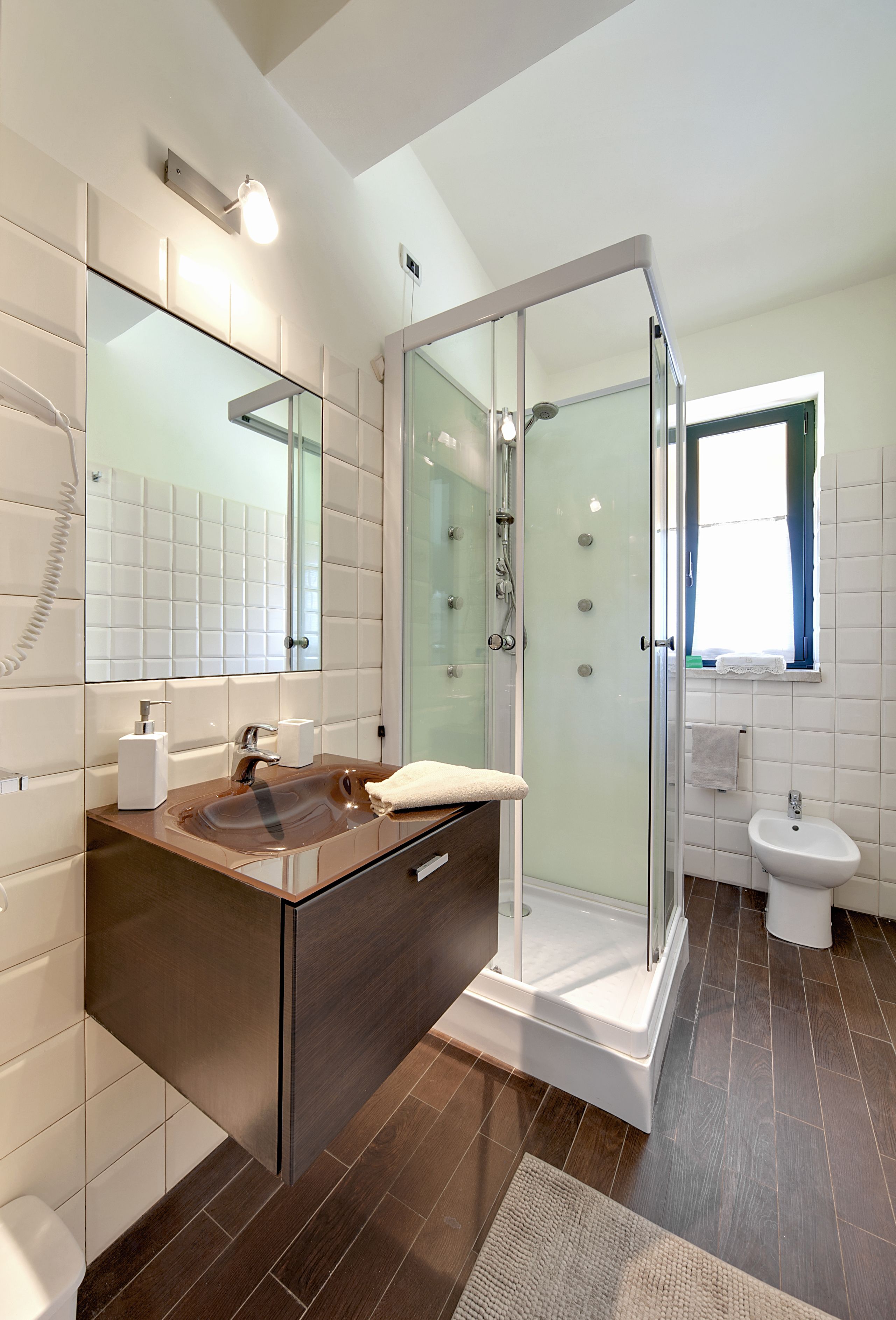 A modern bathroom with a glass-enclosed shower, a vanity with a sink, and a toilet.