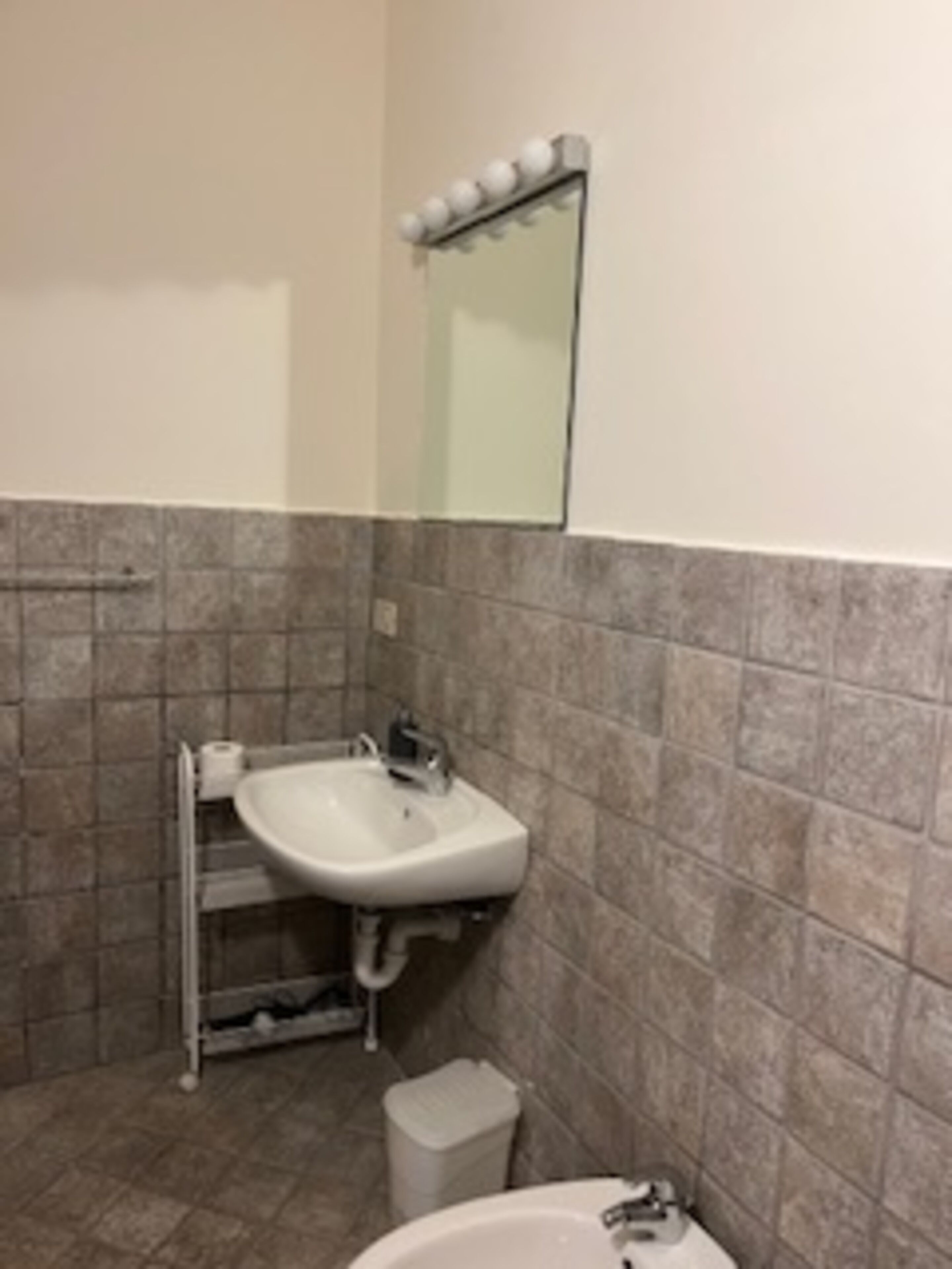 A bathroom with a sink, mirror, and tiled walls.