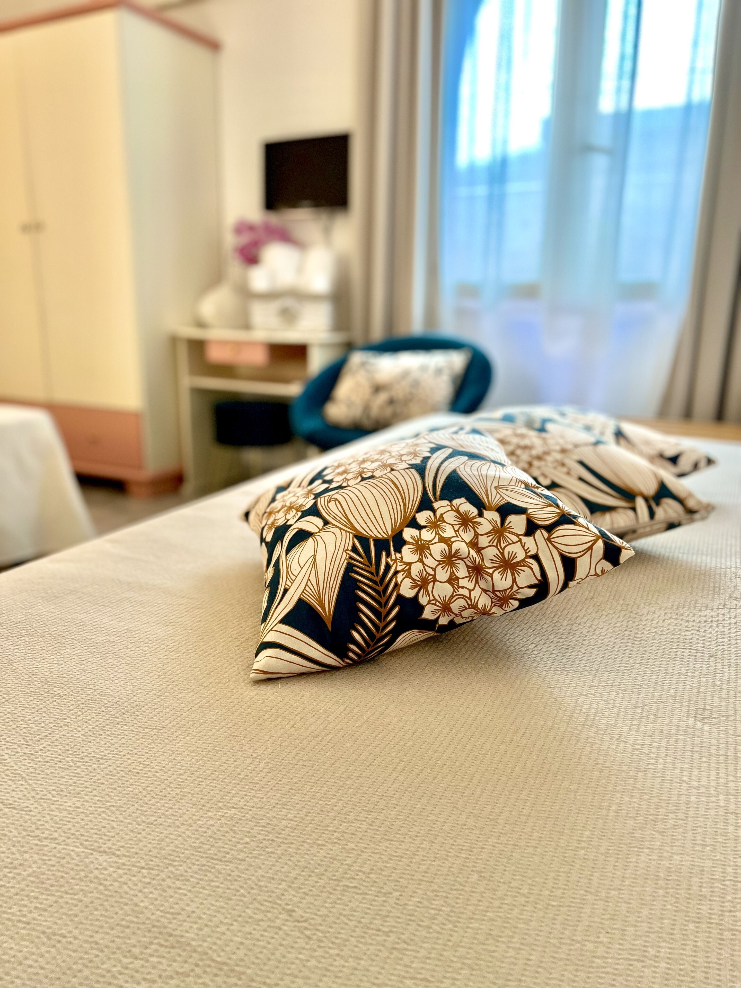 A hotel room with a bed, pillows, a desk, and a chair.