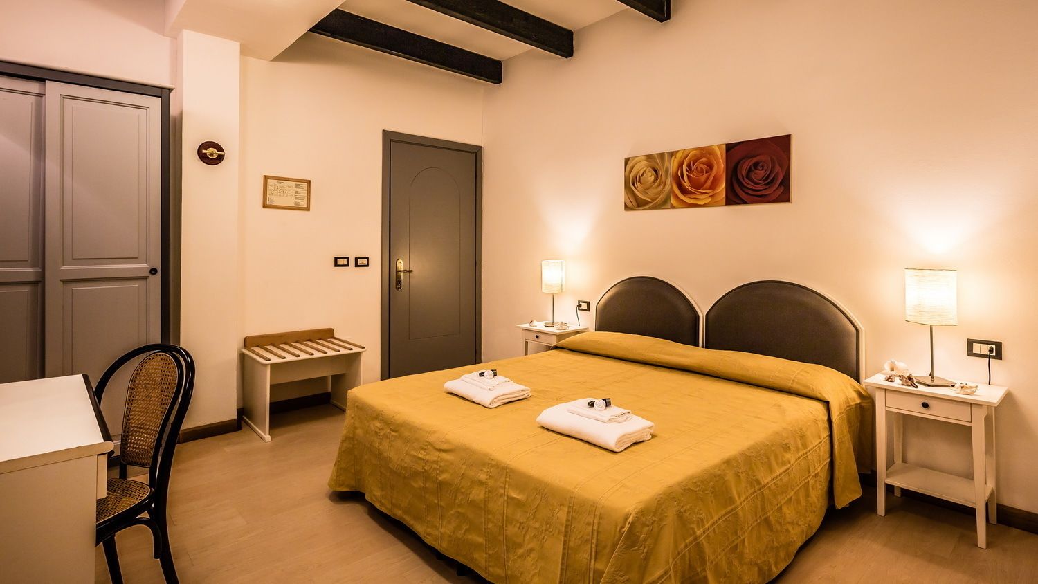 Ein Hotelzimmer mit einem Bett, zwei Nachttischen mit Lampen, einem Sessel, einem Schreibtisch und einer Tür.