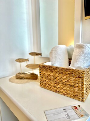 A wicker basket with towels on a white counter. - Hotel Cala di Seta (Calasetta)