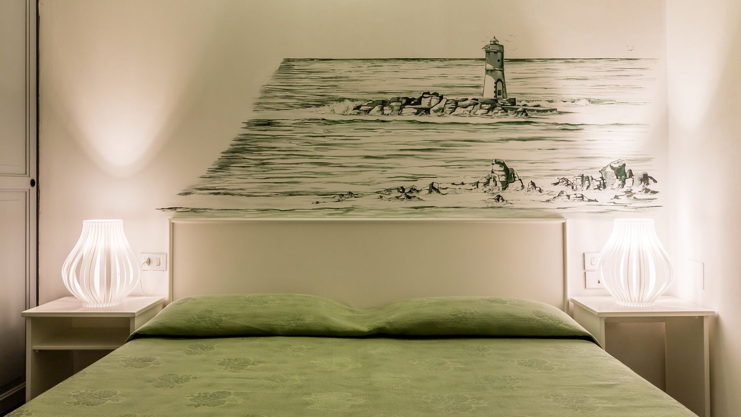 Un dormitorio con una cama, dos lámparas de noche y un cuadro en la pared de un faro.