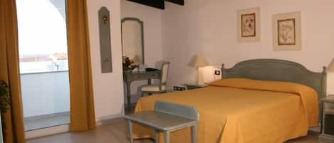A bedroom with a bed, a chair, a desk, a mirror, and a nightstand.