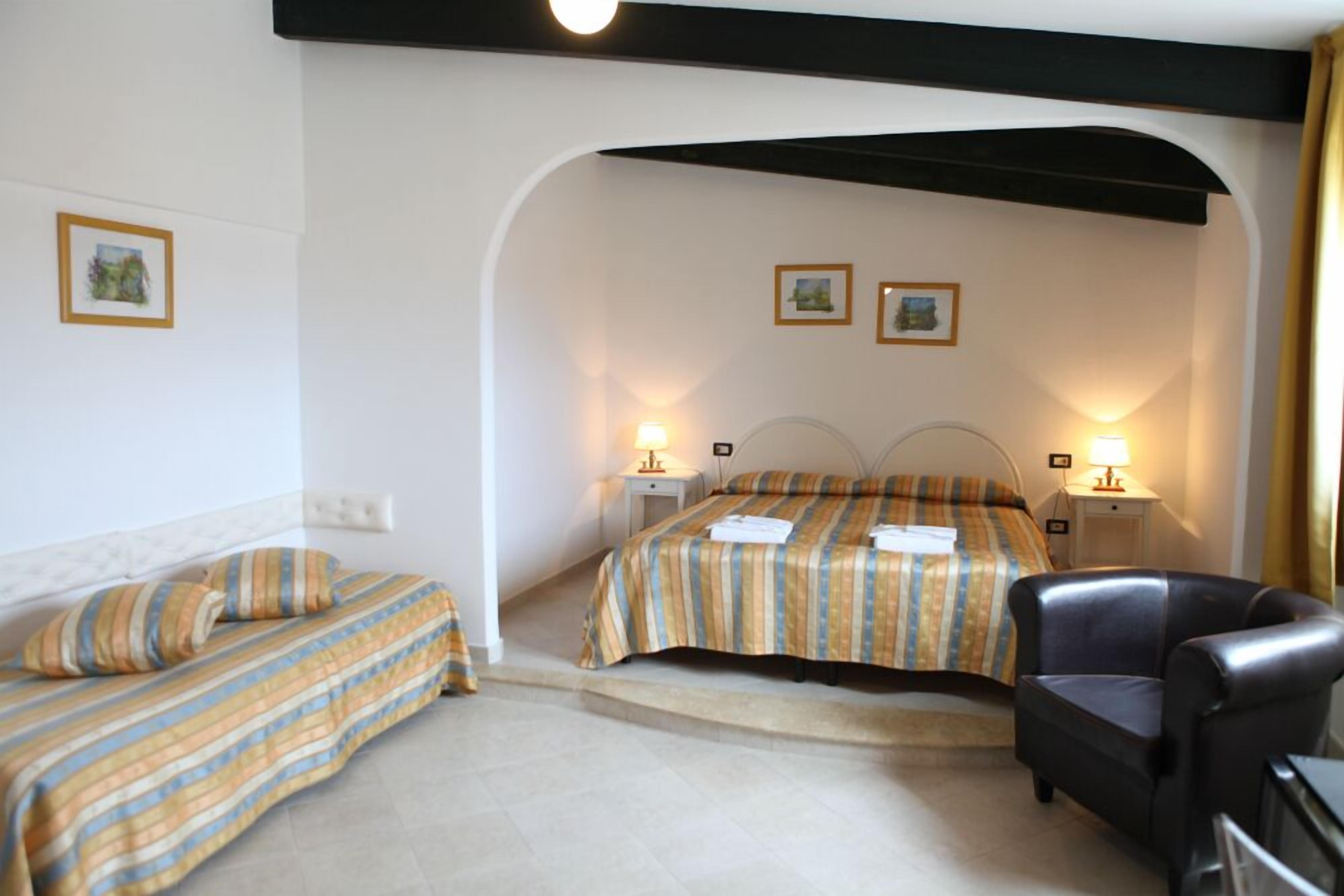 A hotel room with two beds, a chair, and two bedside lamps.