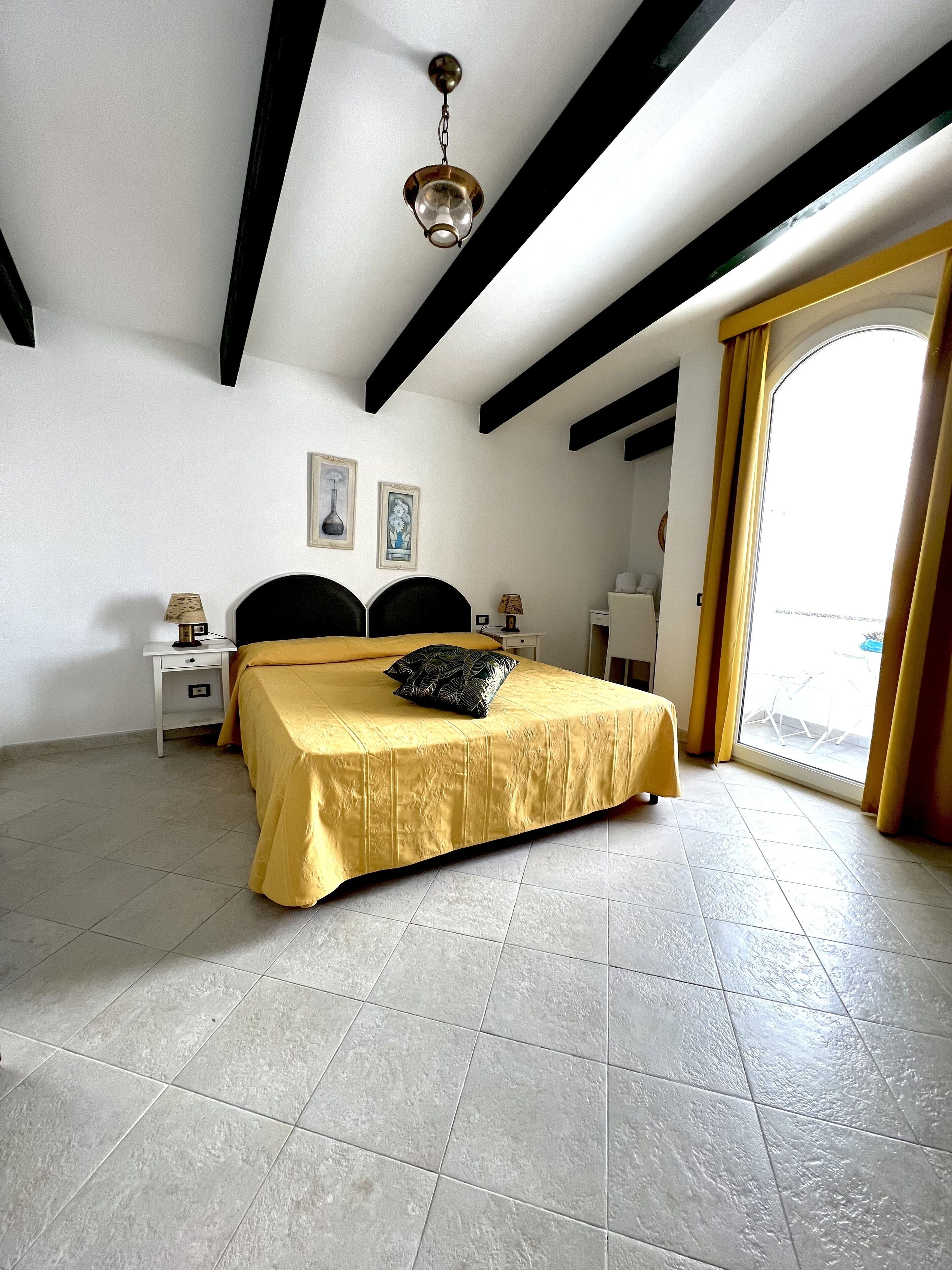 A bedroom with a bed, a nightstand, a lamp, and a ceiling light.
