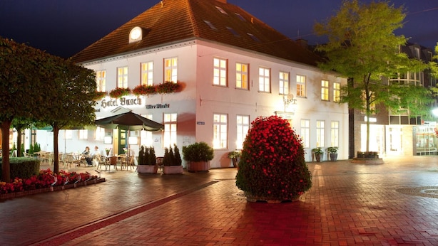 Un hotel de estilo arquitectónico europeo tradicional, con una fachada simétrica, múltiples ventanas y un área de entrada bien iluminada con asientos al aire libre.