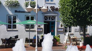Un restaurante con terraza, una fuente y un árbol.
