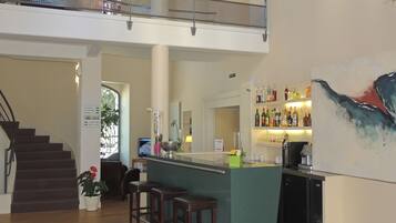 Un interior espacioso con una escalera, una zona de bar con taburetes y un cuadro grande en la pared.