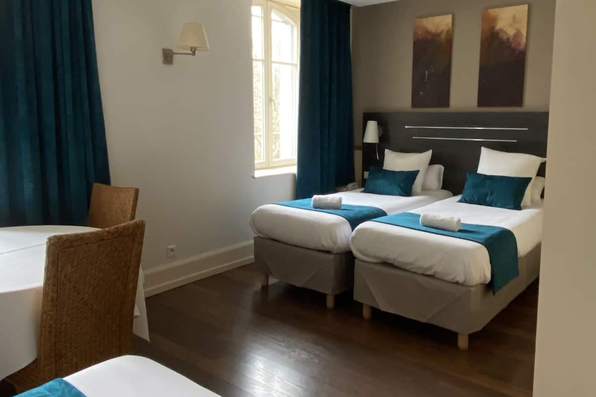 Een hotelkamer met twee bedden, een eettafel en een stoel.