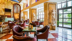 A spacious lobby with marble floors, leather seating, and large windows offering a view of the outdoors.