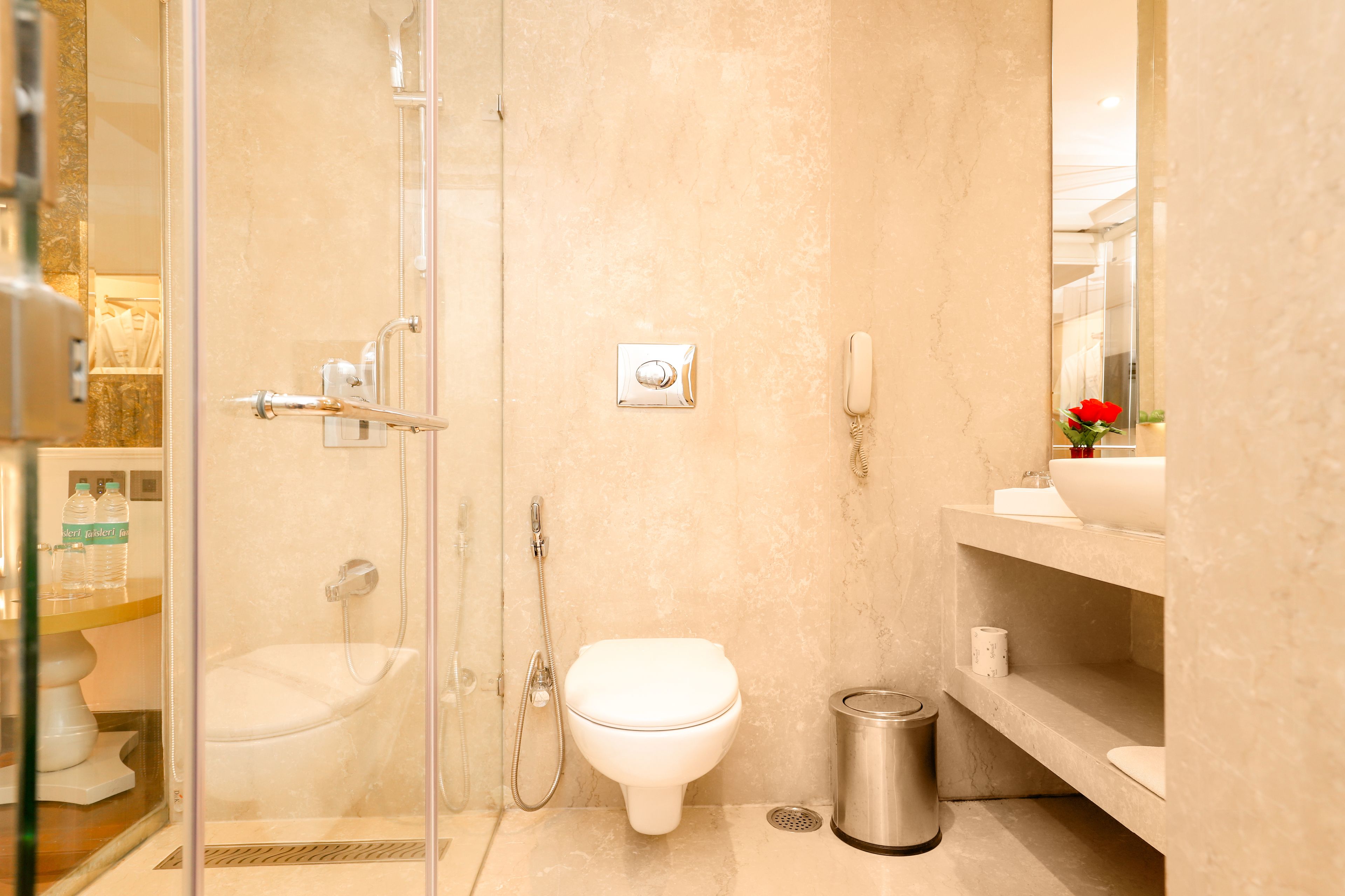 A modern bathroom with a glass-enclosed shower, a white toilet, a sink, and a trash can.