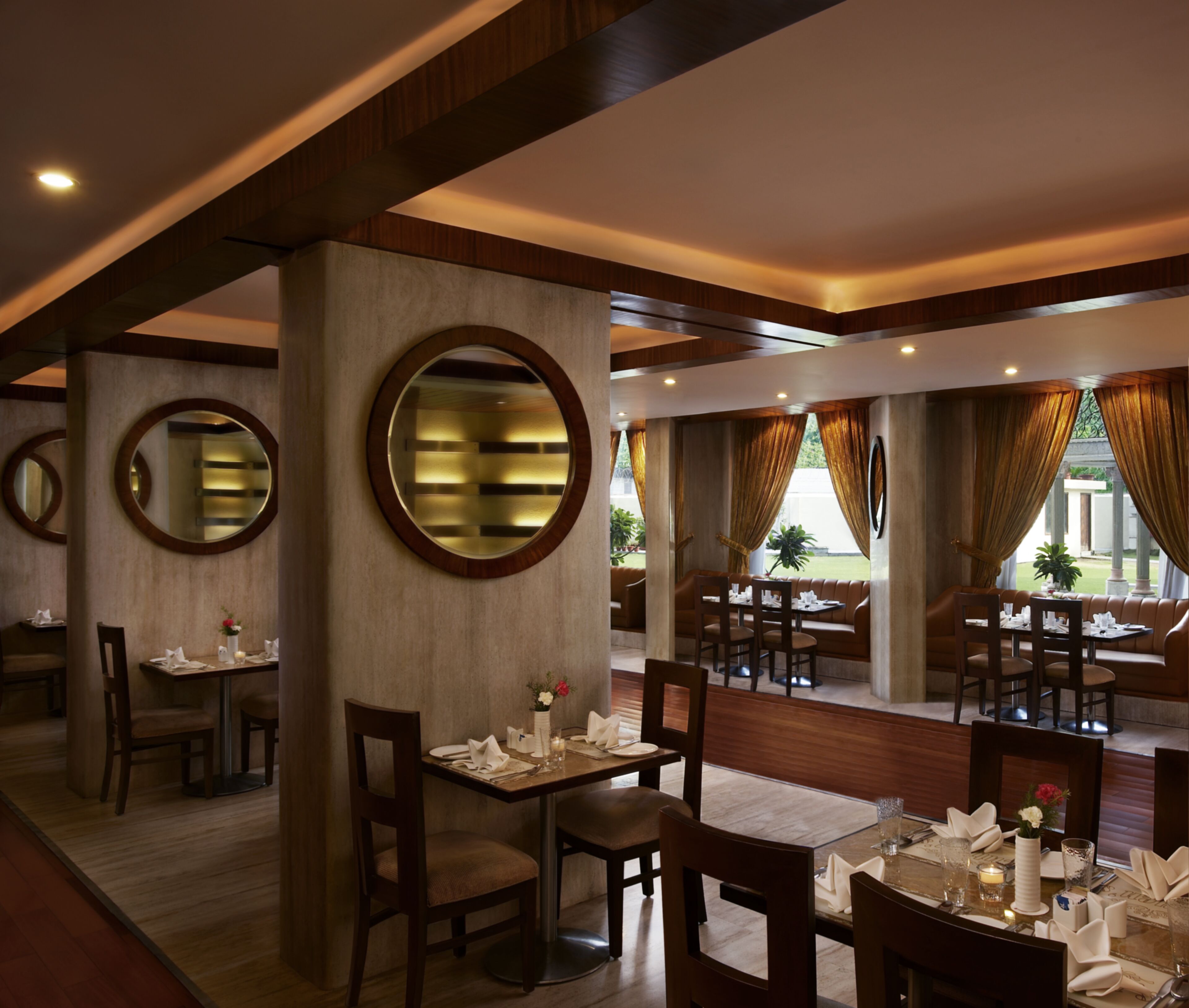 A restaurant with round mirrors, wooden furniture, and a view of the outdoors.