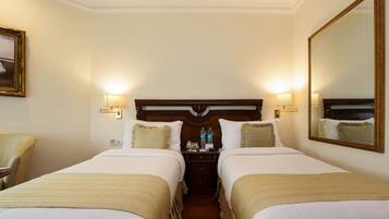 Una habitación de hotel con dos camas, una mesita de noche, un espejo y una silla.