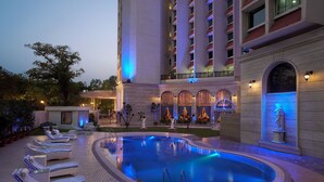 A hotel pool area with lounge chairs, a fountain, and a statue.