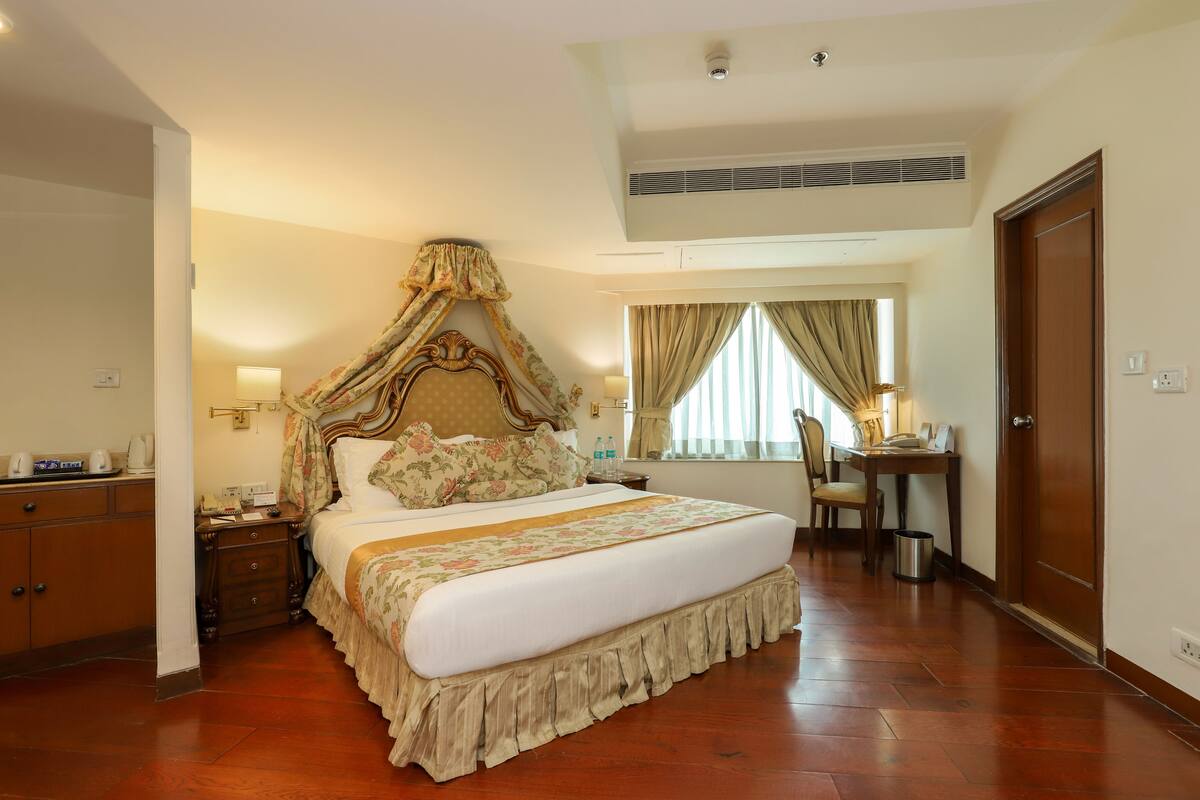 A spacious bedroom with a large bed, a desk, and a chair.