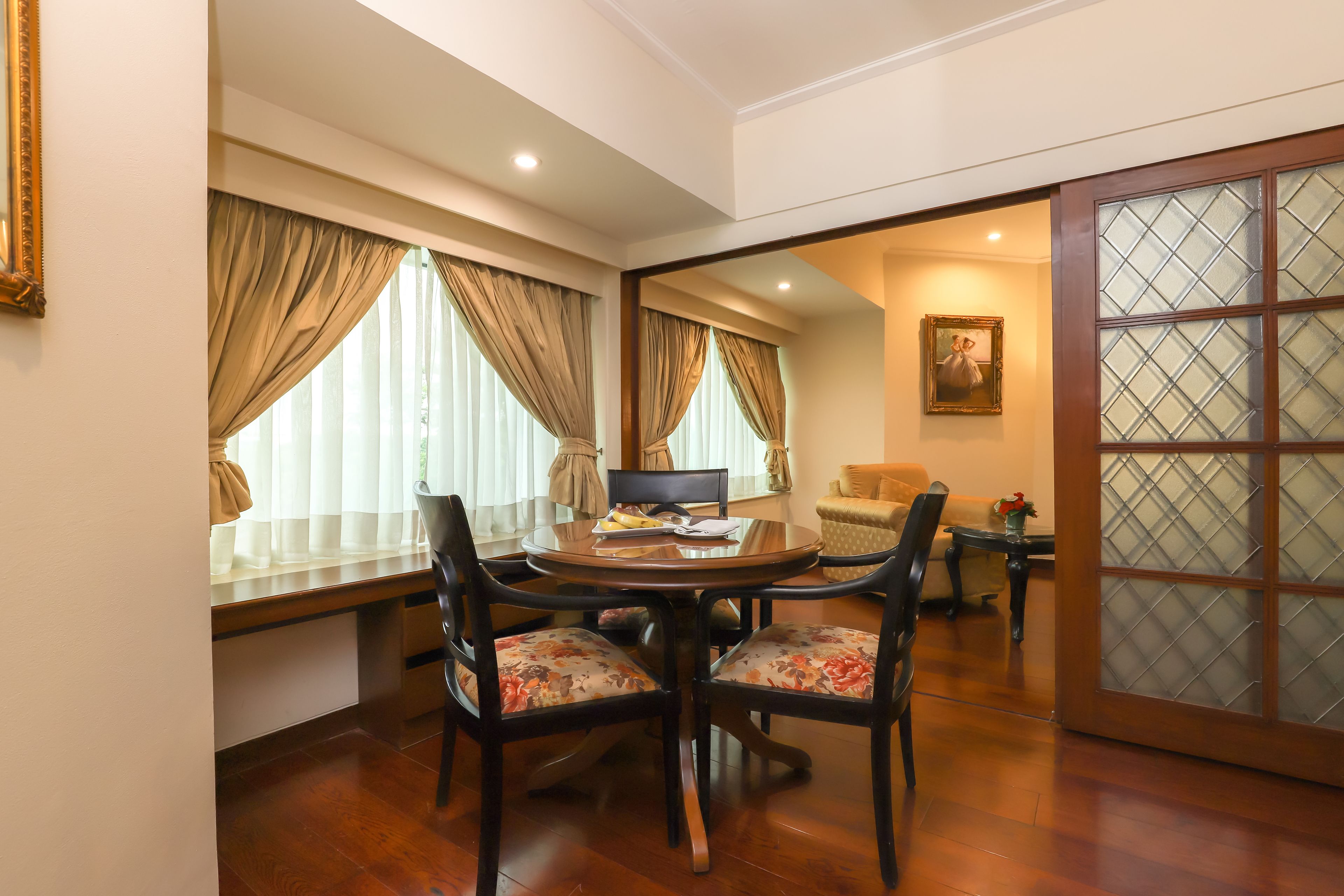 A dining area with a round table, four chairs, and a television.