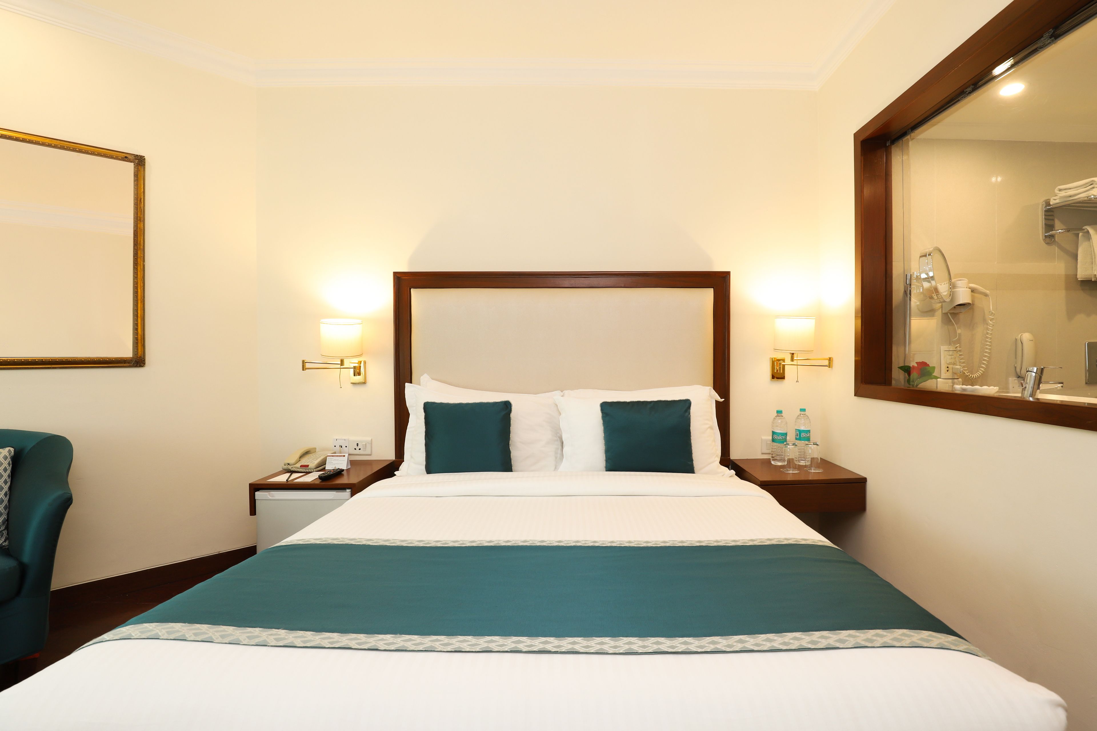 A hotel room with a large bed, two bedside tables, a chair, and a mirror.