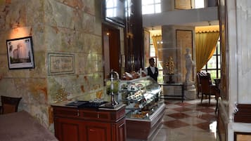 Ein Tee-Salon mit Marmorwand, einer Theke mit Gebäck und einer Statue.