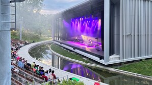 Um anfiteatro ao ar livre com palco, assentos para o público e um elemento aquático.
