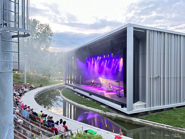 Un amphithéâtre en plein air doté d’une scène, de places pour le public et d’un élément décoratif aquatique.