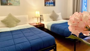 Quarto de hotel com duas camas, mesa de cabeceira com abajur e obras de arte nas paredes.