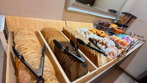 A bakery display with various breads and pastries, including sliced bread and pastries with toppings.