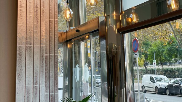 Une entrée moderne avec des portes en verre, un éclairage intérieur et une vue sur la rue.