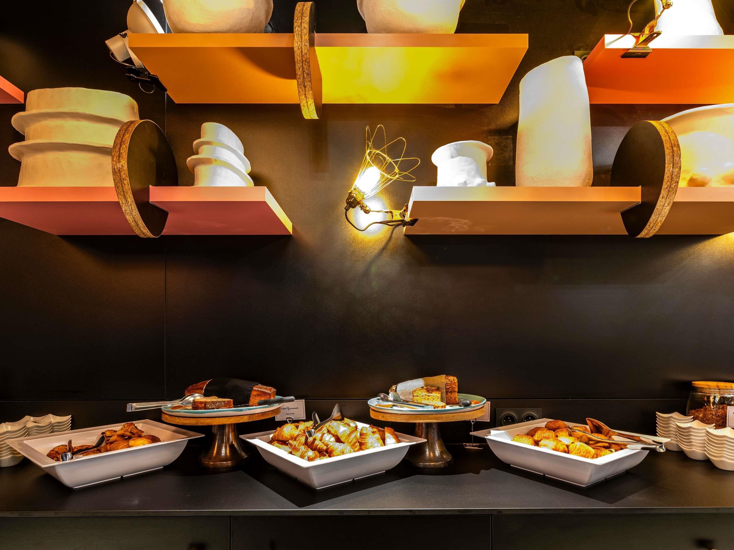 Disposição de buffet com diversos alimentos e uma luminária moderna.