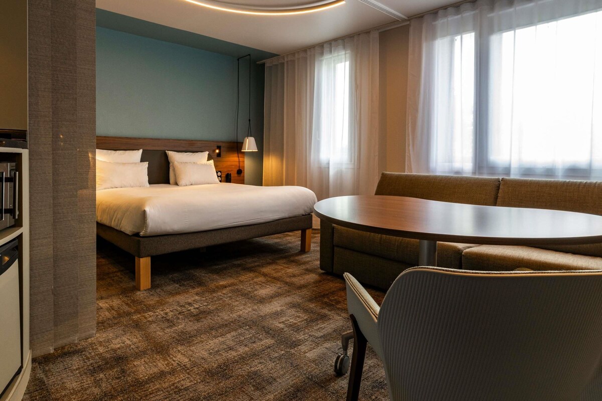 Una habitación de hotel con cama, sofá, mesa redonda y escritorio.