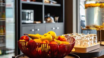Un frutero sobre una mesa, con una cocina al fondo.